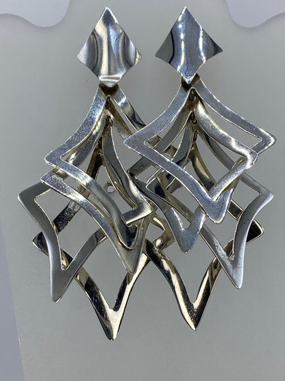 Aretes de plata calado geométrico escalonado, vistos de frente mostrando el diseño de capas