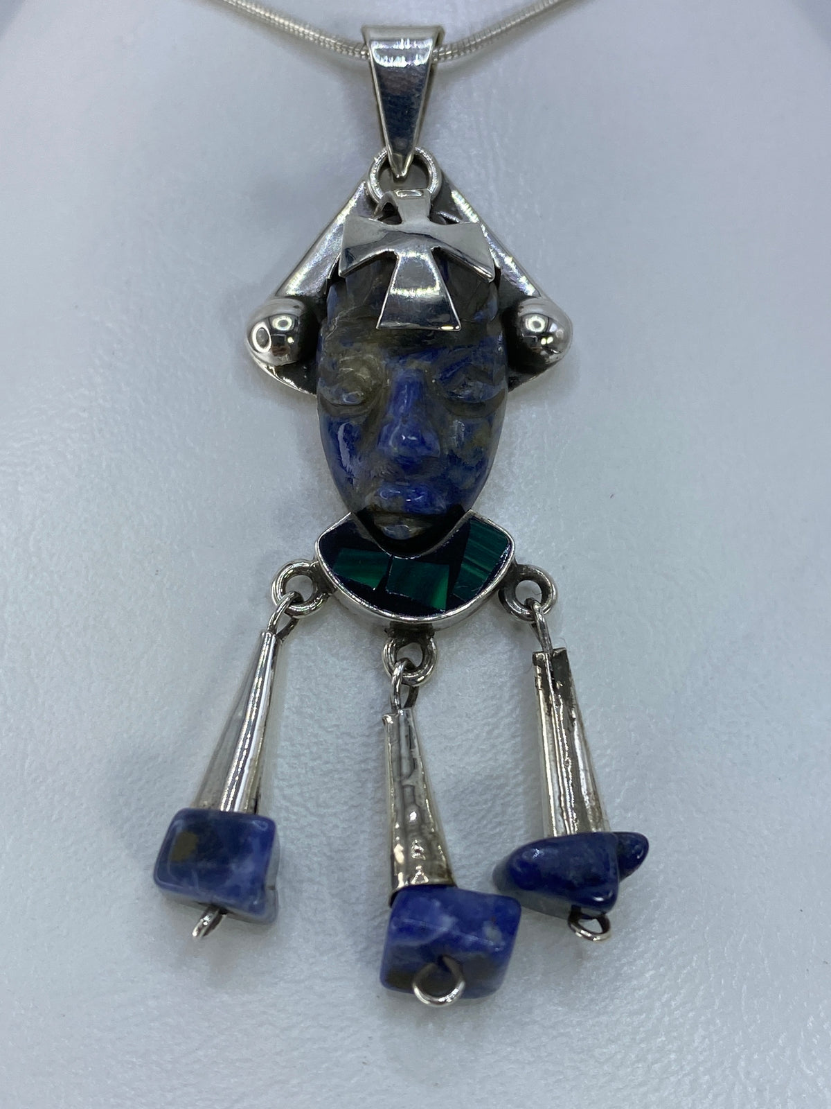 Detalle frontal del rostro prehispánico con cruz central y piedra azul brillante