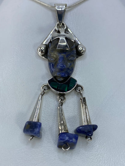 Detalle frontal del rostro prehispánico con cruz central y piedra azul brillante