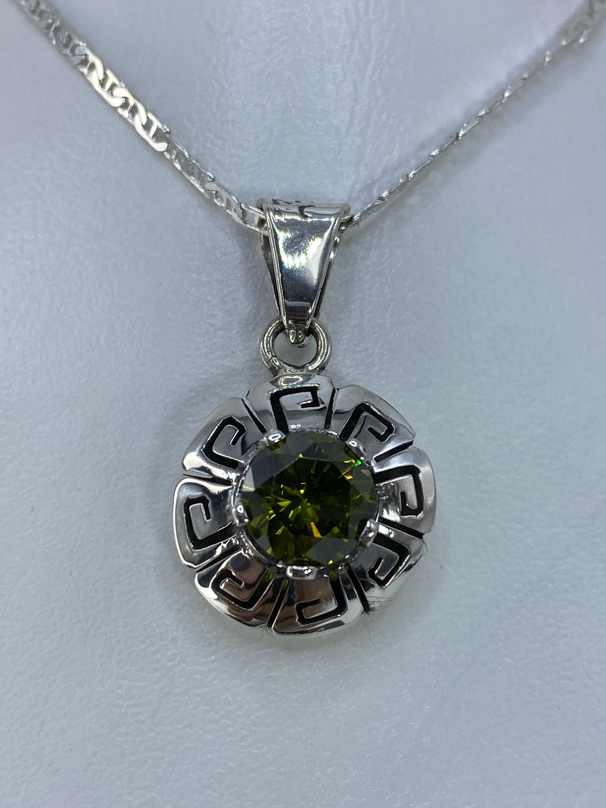 Detalle frontal del dije mostrando la circonia facetada verde olivo engastada