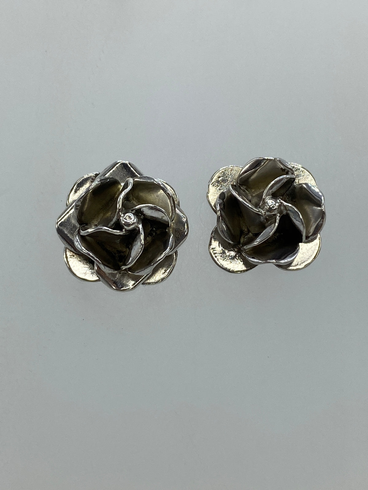 Detalle de los aretes de rosa floral en plata, vista frontal