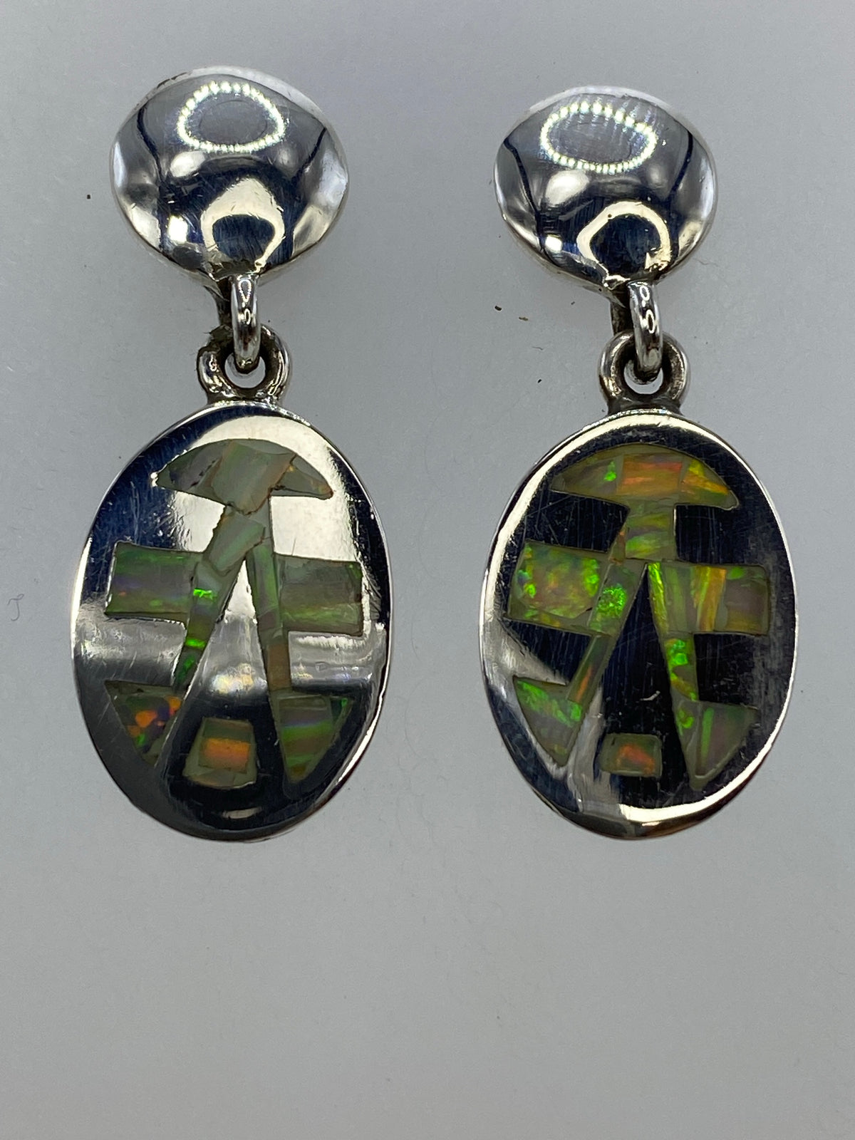 Par de aretes de plata 950 con ópalo de fuego multicolor engastado, vista frontal mostrando los colores verde y naranja de las piedras