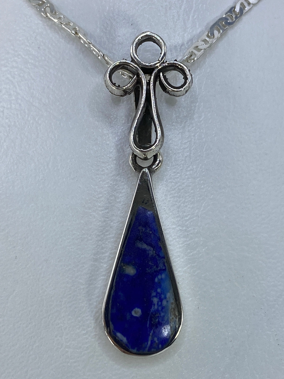Detalle frontal de la cruz de plata 925 con engaste de piedra azul a mano