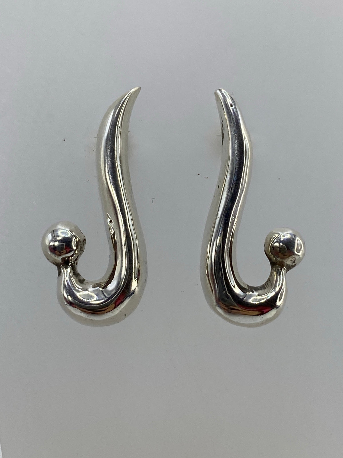 Detalle de los aretes cartoneado mostrando la técnica de lámina de plata y el acabado espejo