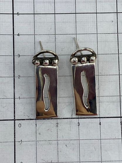 Pair of minimalist cartoneado silver earrings on white background, geometric design