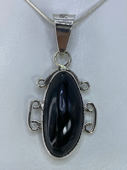 Dije de plata 950 con onix negro engastado en marco de espiral plateado