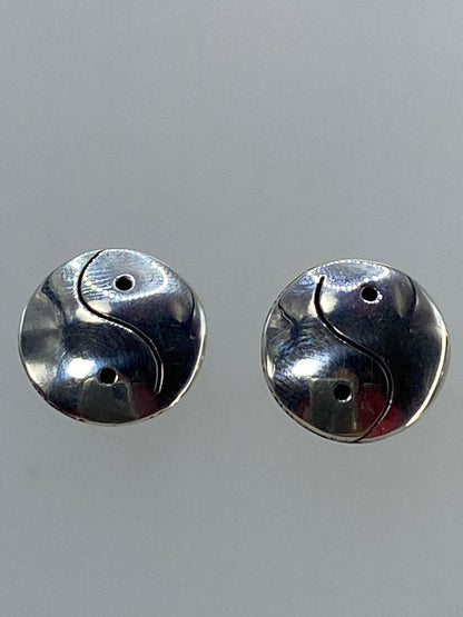 Aretes Yin Yang colocados sobre fondo azul para escala visual