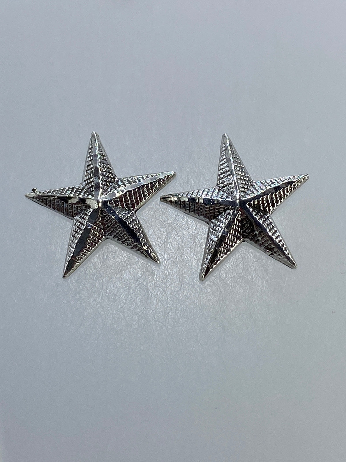 Detalle del relieve profundo y la textura del repujado en los aretes estrella