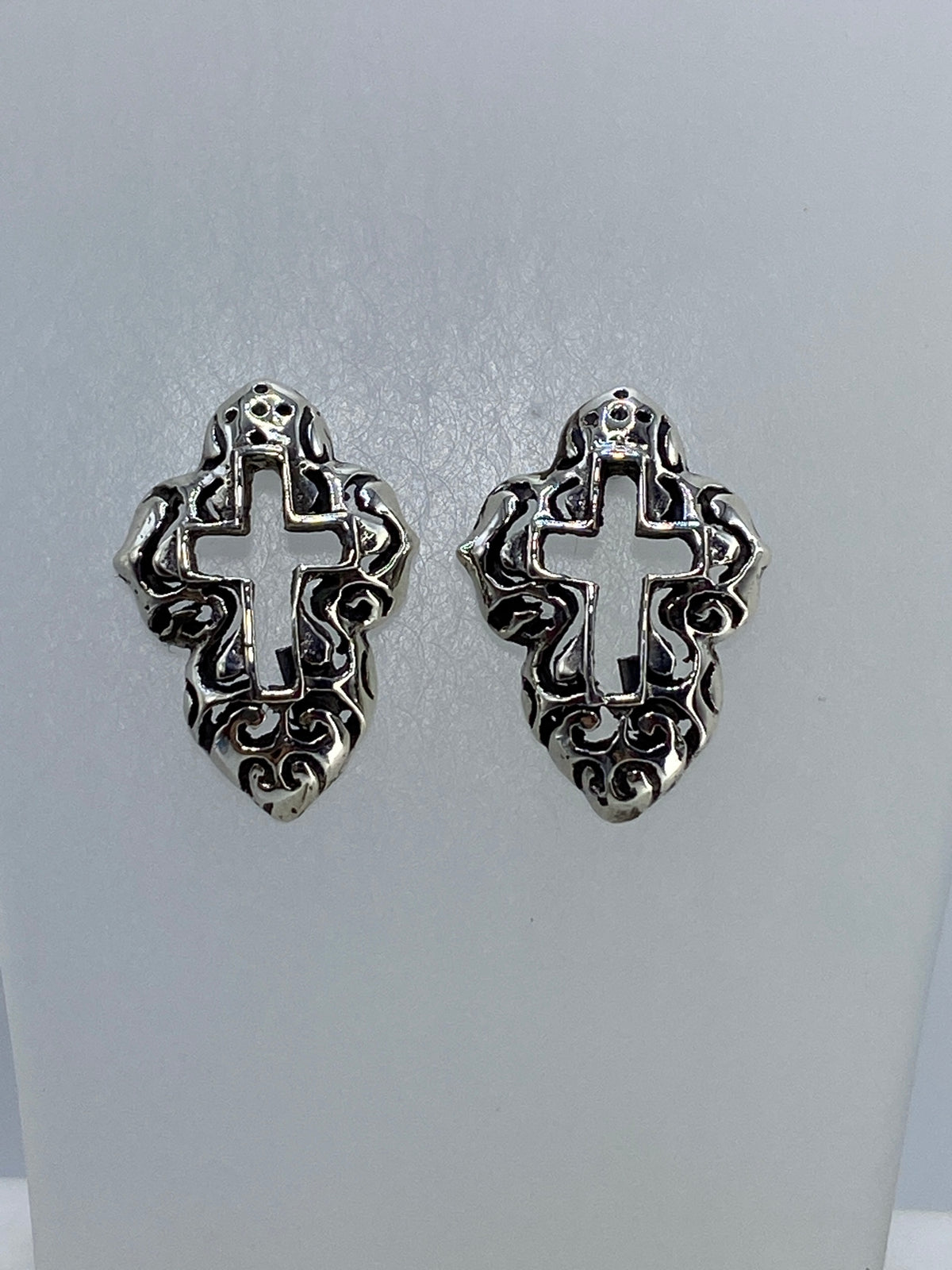 Vista frontal de aretes de plata con técnica de calado y diseño de cruz