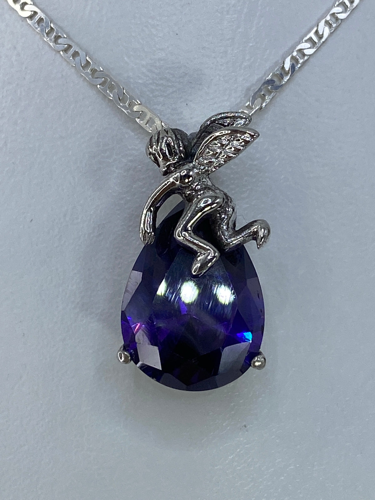 Dije ángel de plata con circonia morada engastada, colgando en cadena visible en la foto