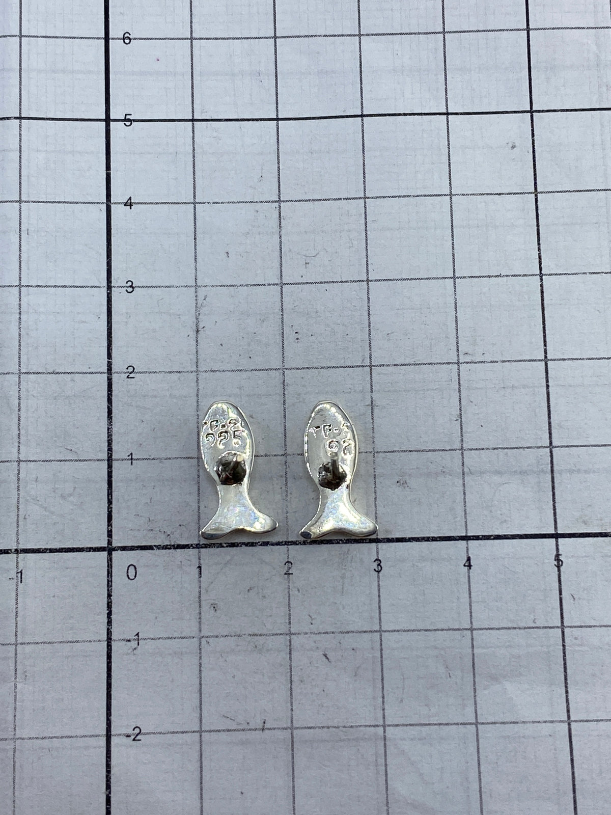 Aretes sobre fondo neutro mostrando el Quinto 925 en la base