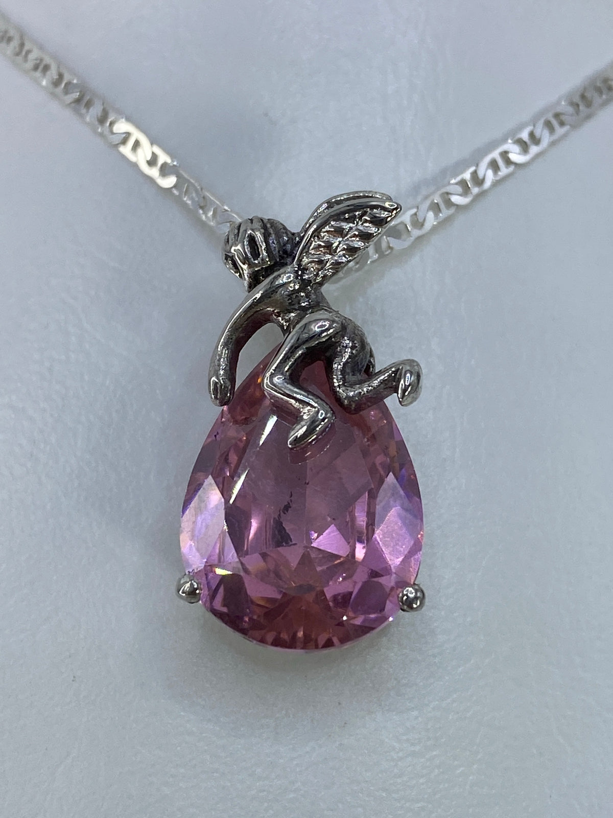 Detalle frontal del ángel: circonia rosa brillante engastada en plata de Taxco