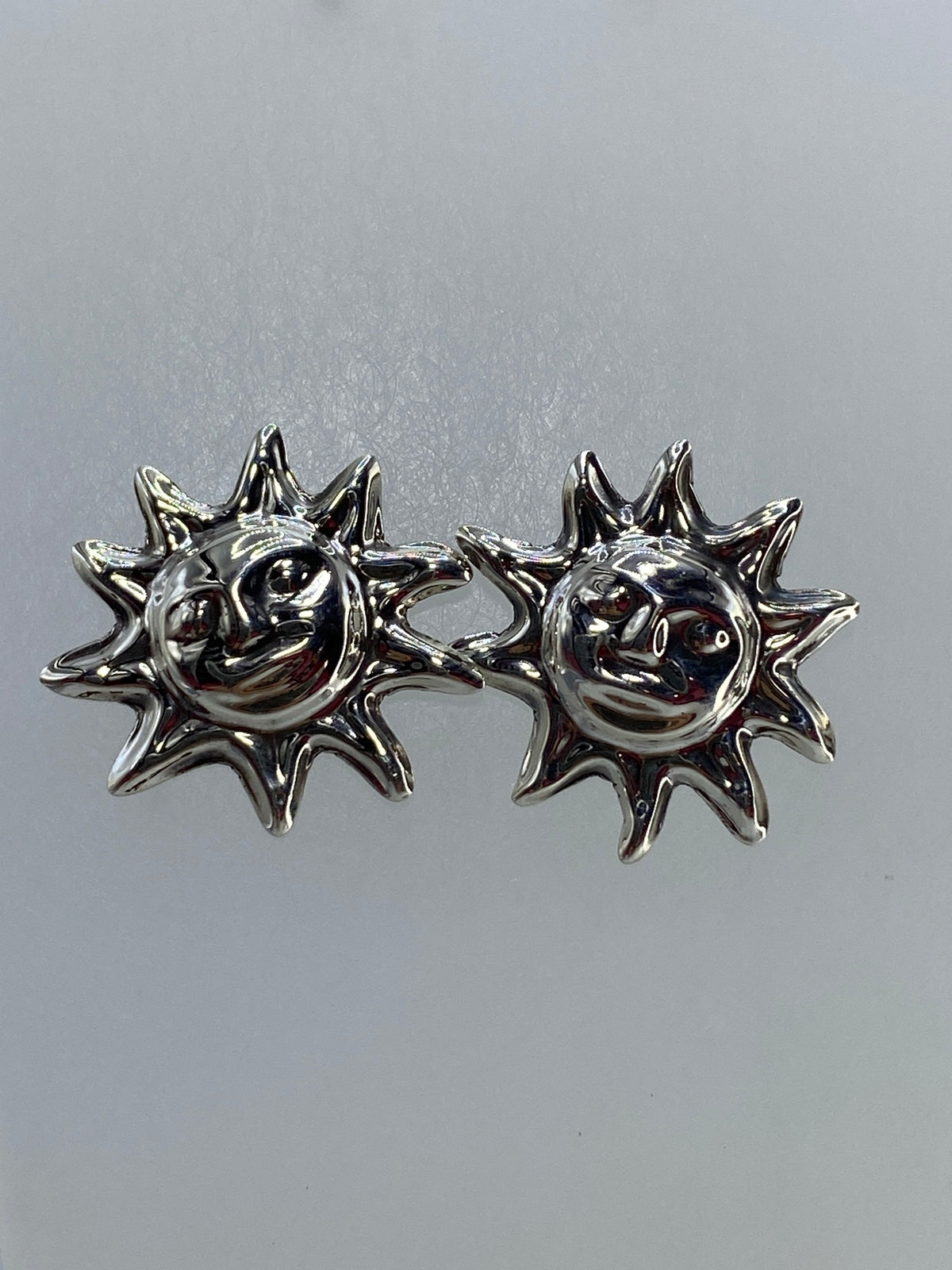 Detalle frontal de los aretes solares mostrando el volumen 3D y el pulido brillante de la plata 925