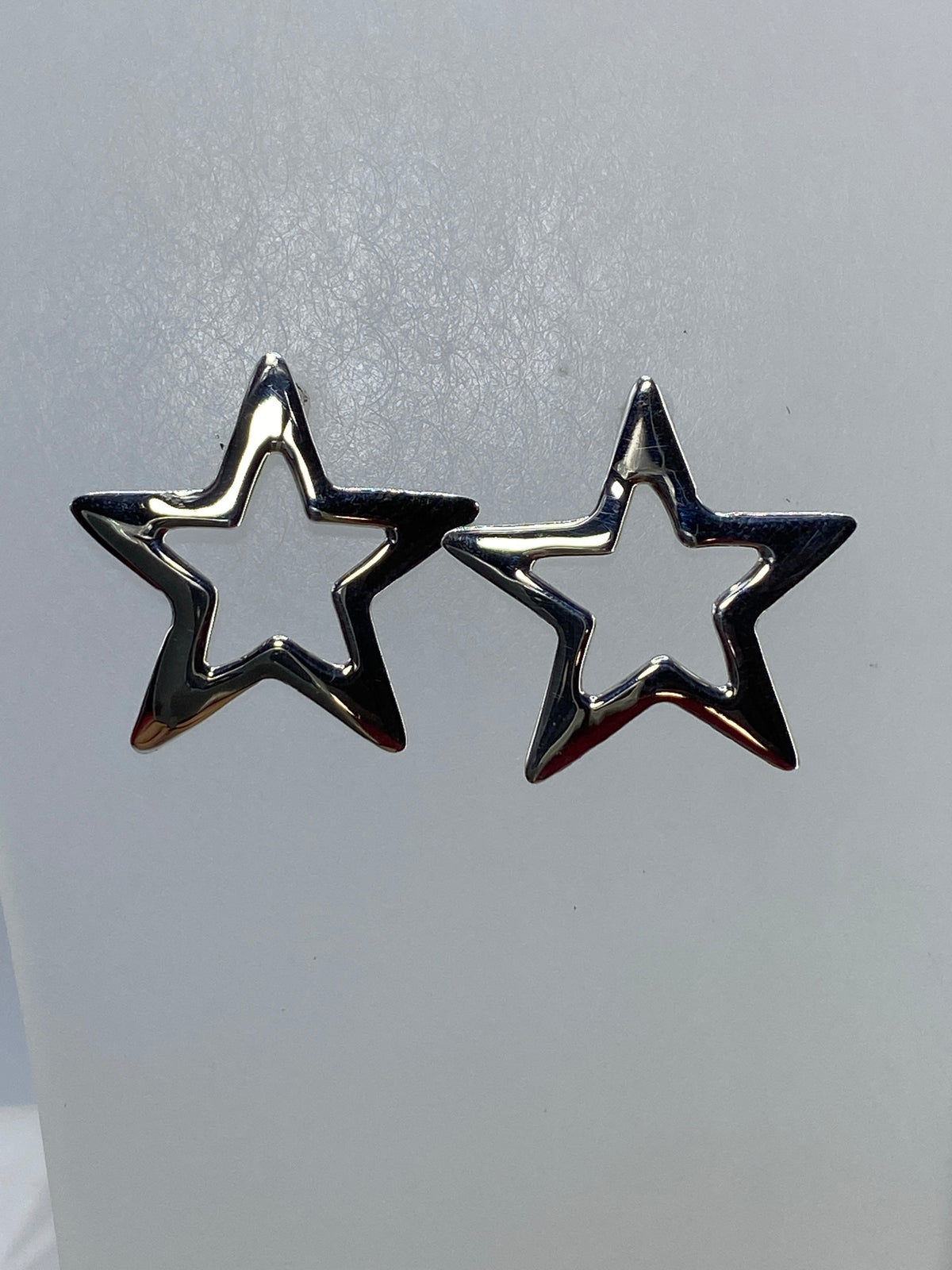 Aretes estrella de plata de Taxco brillando contra fondo neutro