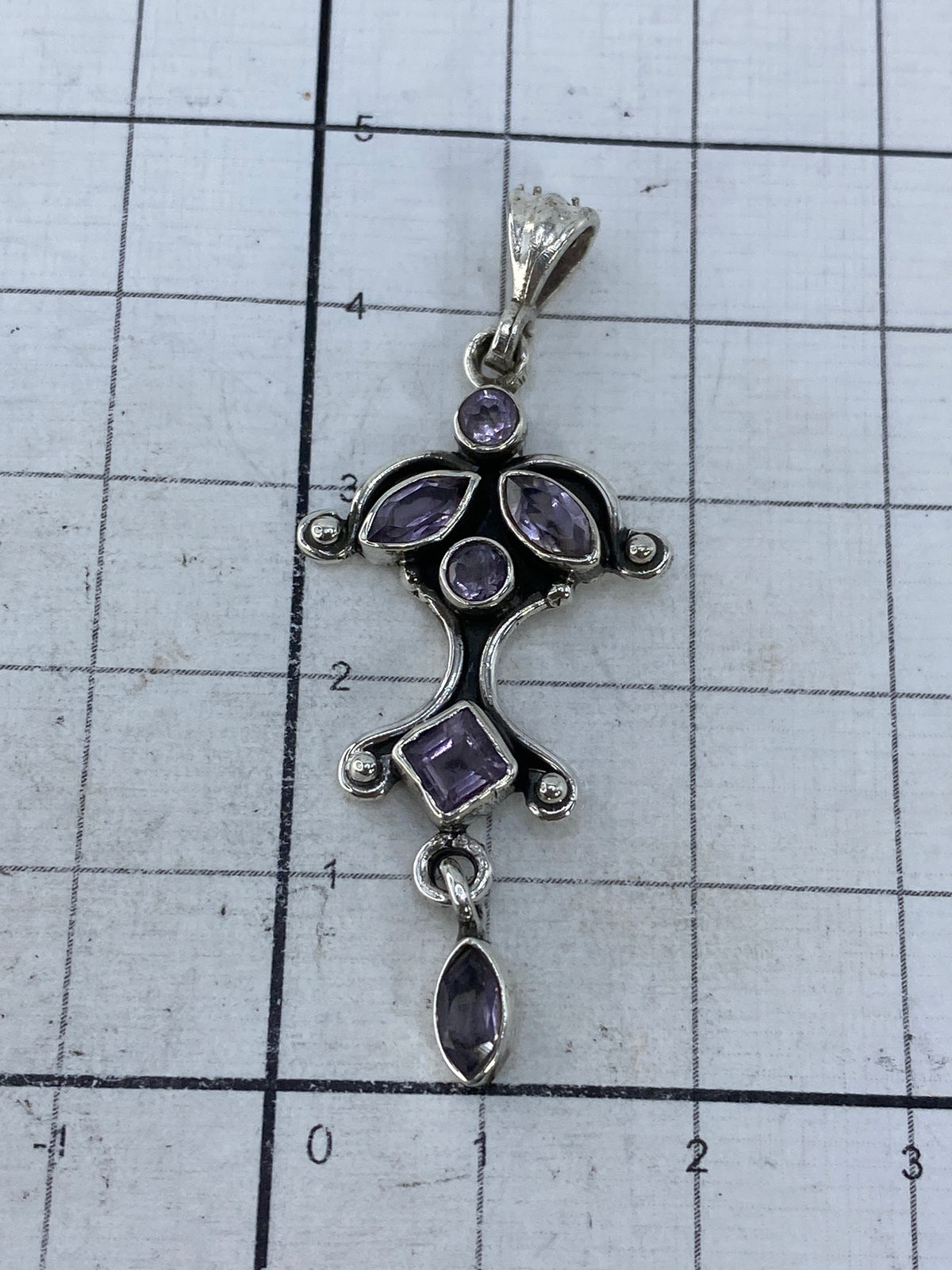 Dije de plata sobre fondo blanco con escala de medidas, mostrando tamaño real 4.5 cm × 2 cm