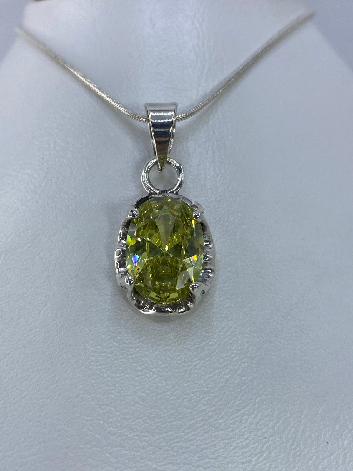 Vista frontal del dije oval con circonia facetada en verde olivo