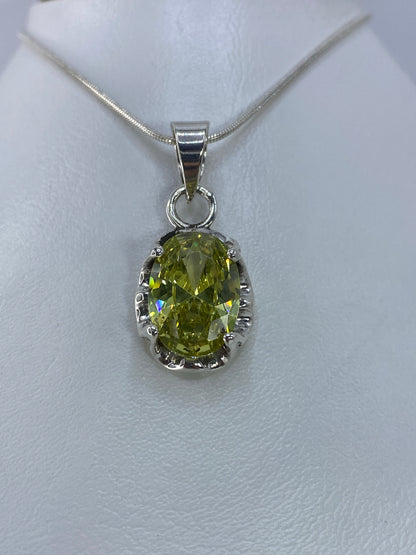 Vista frontal del dije oval con circonia facetada en verde olivo
