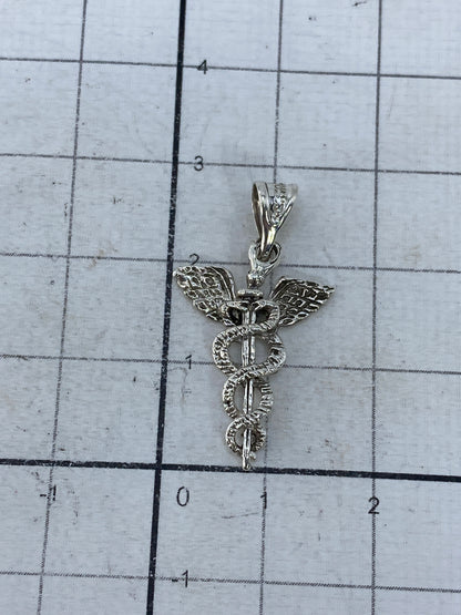 Dije caduceo de plata 925 en balanza de precisión mostrando 1.5 gramos