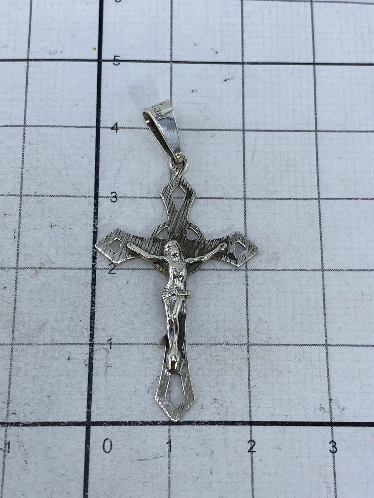 Crucifijo de plata en escala de centímetros, mostrando tamaño real de 4.3 cm de largo