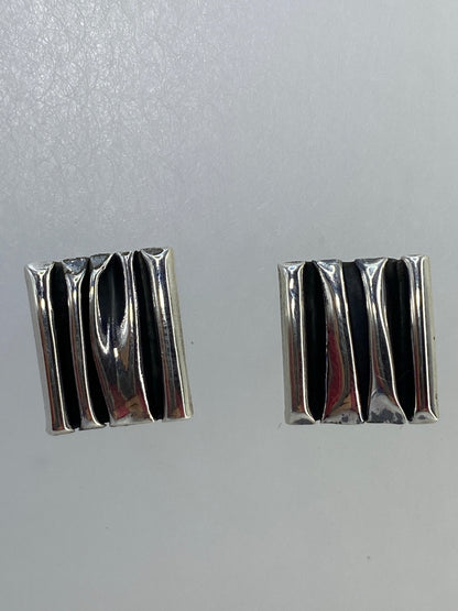 Detalle del cartoneado: pliegues de plata trabajada a mano en cada arete