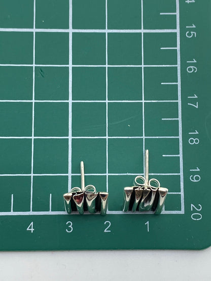 Aretes de plata maciza sin piedra sobre fondo neutro con medida de referencia