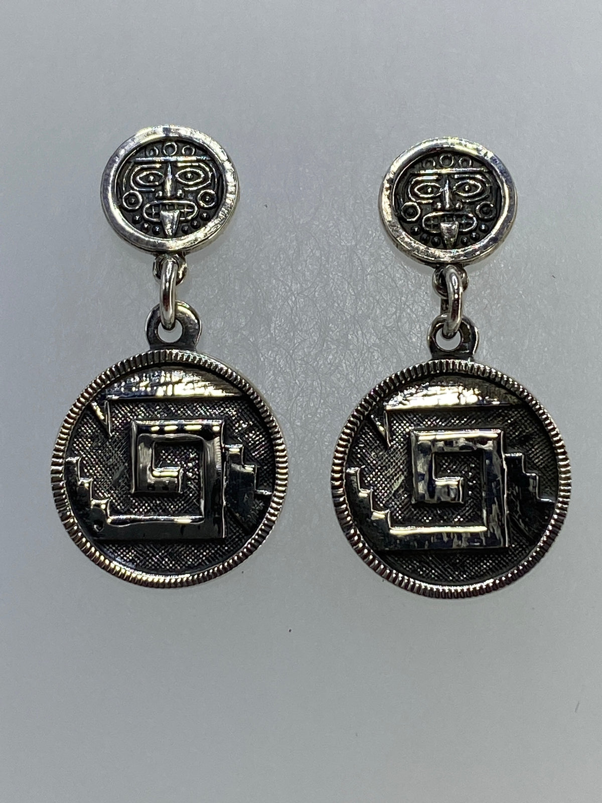 Par de aretes de plata 925 con repujado de glifo prehispánico, visto de frente