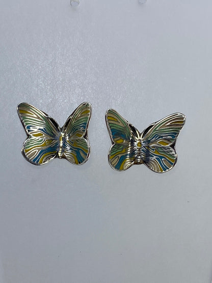 Vista frontal de arete de mariposa de plata con volumen 3D y patina