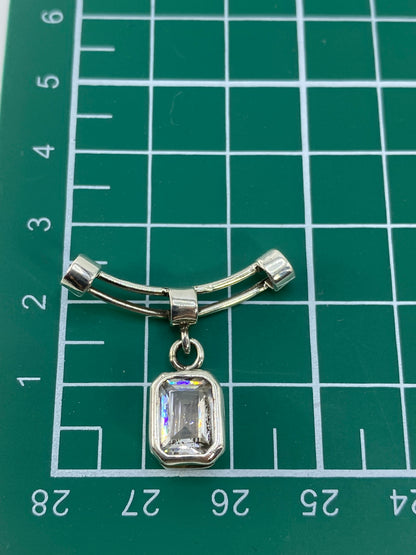 Dije sobre regla de centímetros, mostrando tamaño real de 2.6 × 2.4 cm
