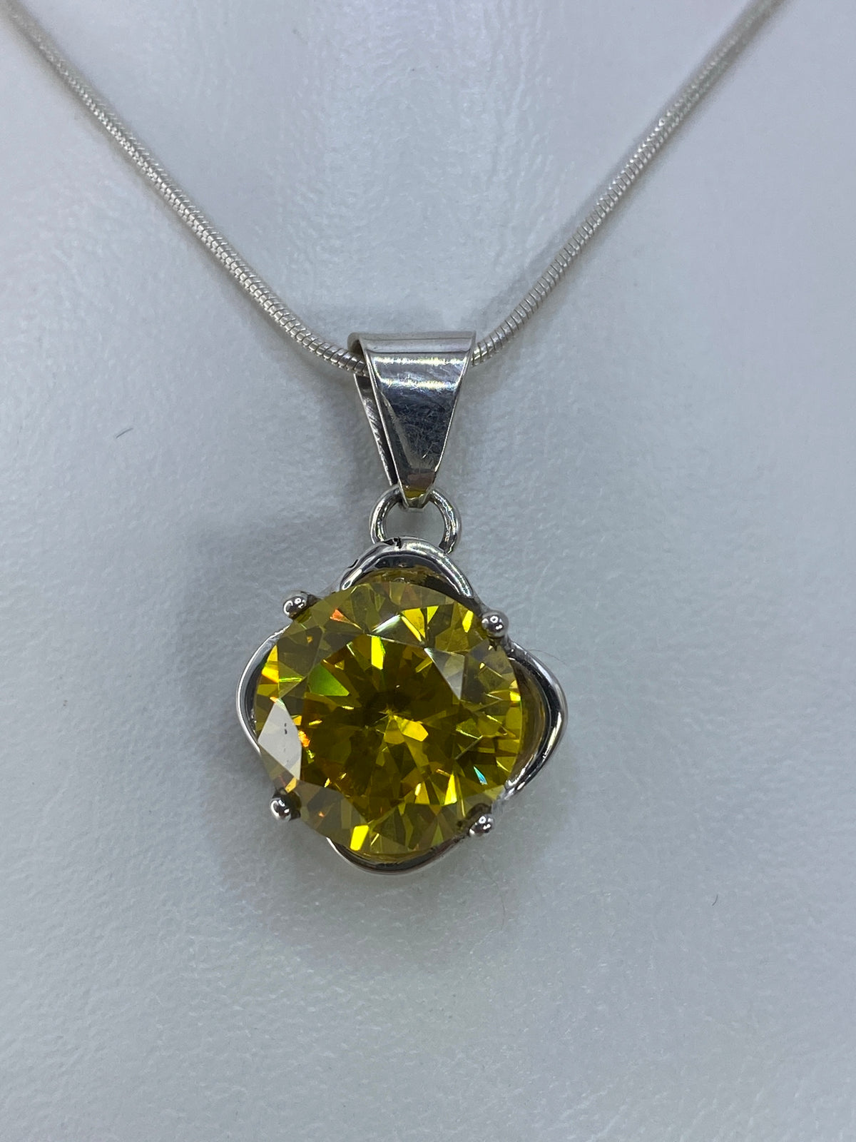 Dije de plata con circonia amarilla engastada en diseño floral, sobre cadena de plata fina