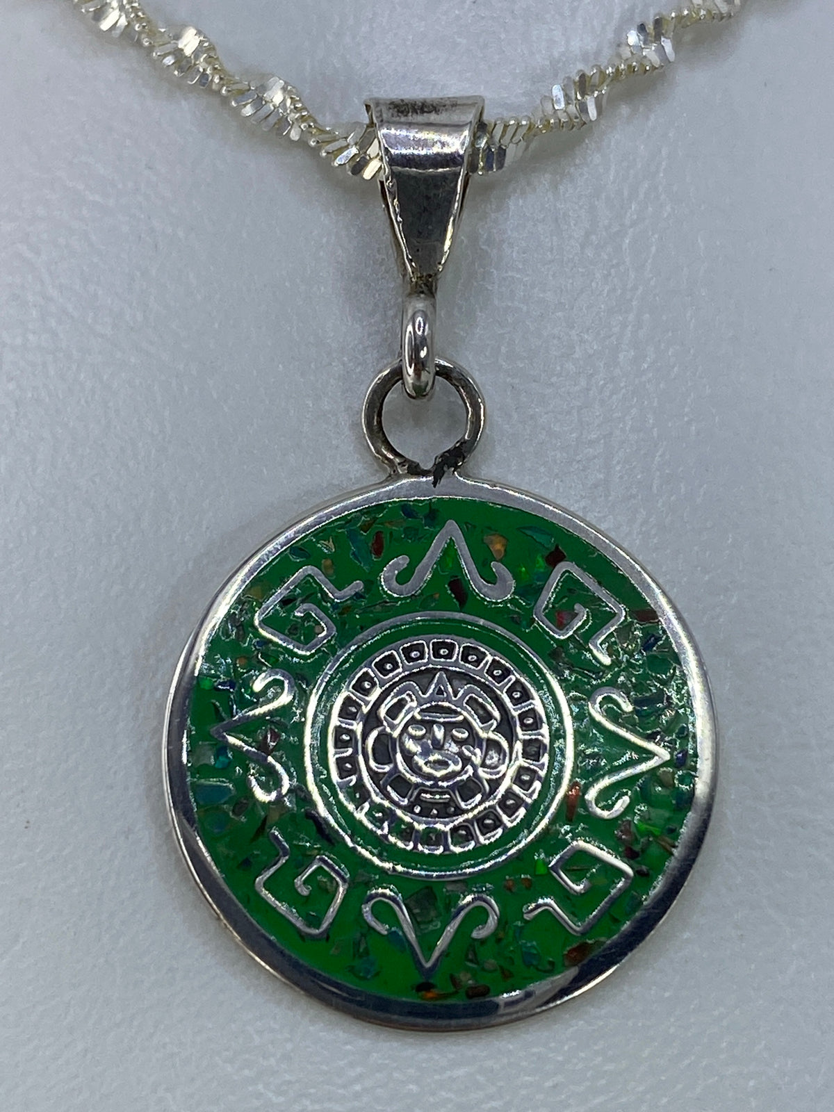 Detalle del dije mostrando el calendario prehispánico grabado en plata 925 y el ópalo de fuego incrustado