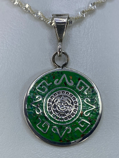 Detalle del dije mostrando el calendario prehispánico grabado en plata 925 y el ópalo de fuego incrustado