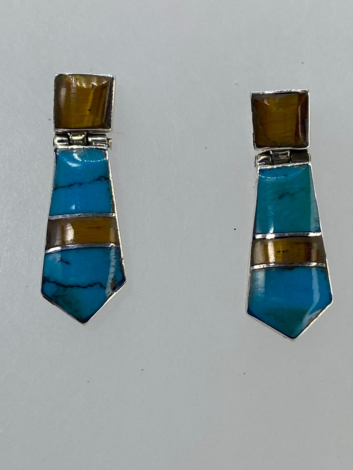 Par de aretes de plata 925 con turquesa azul e ojo de tigre café, sobre fondo blanco