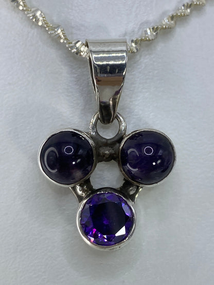 Dije de plata con tres esferas de circonia morada, dos lisas y una facetada, en cadena plateada