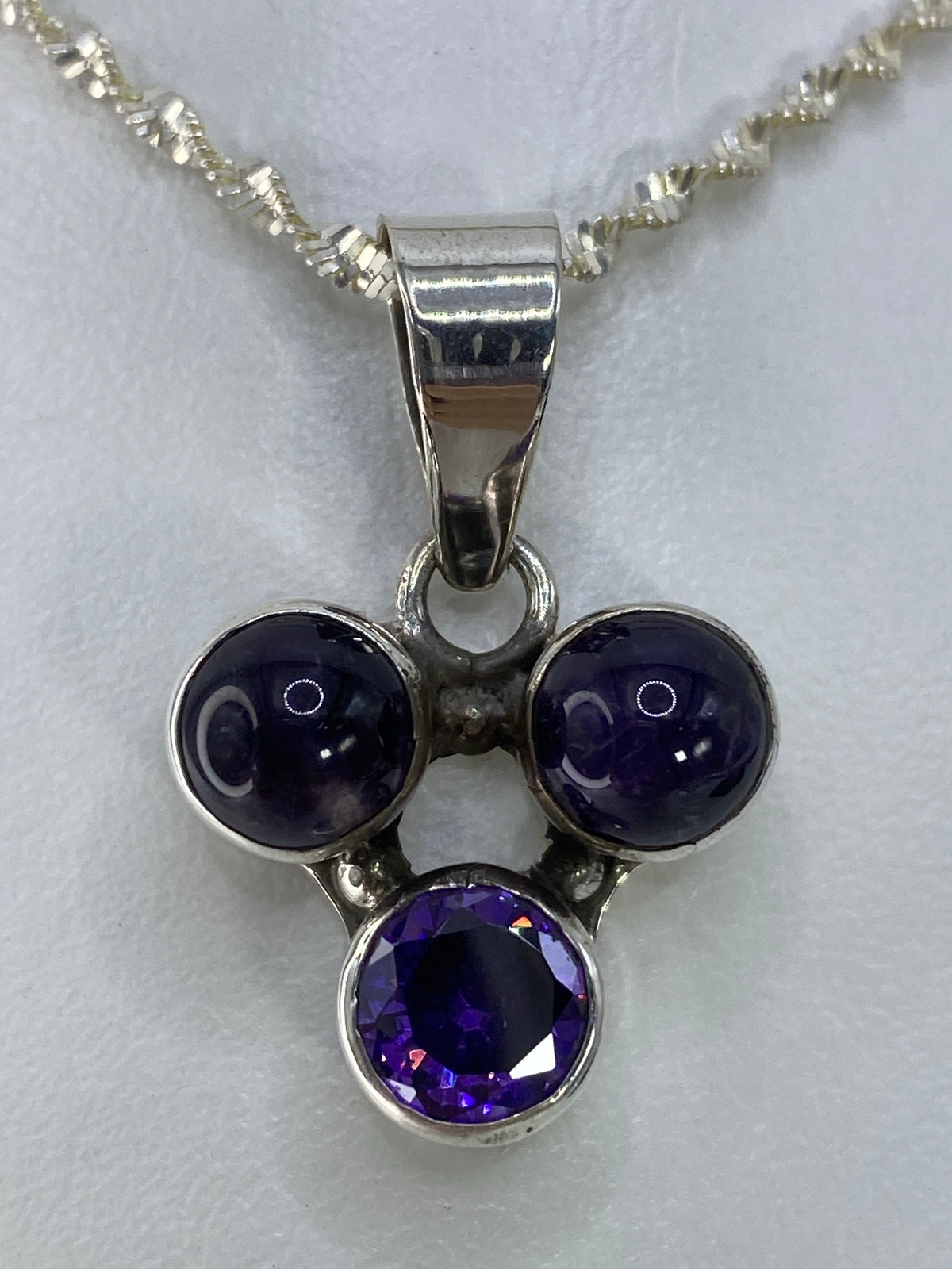 Detalle frontal del dije de circonia morada mostrando el engaste a mano en plata 925
