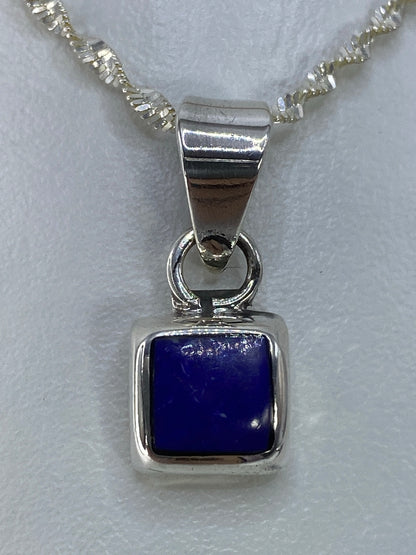 Dije cuadrado de plata con piedra azul engastada, colgando de cadena