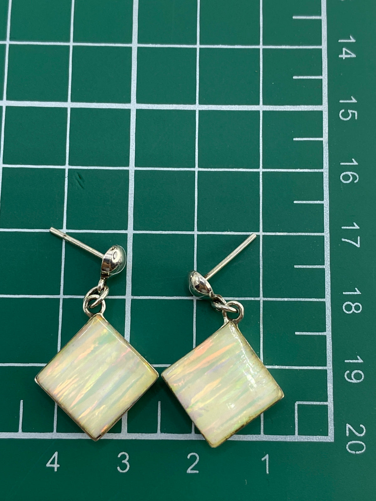Par de aretes en estuche azul sobre balanza de precisión