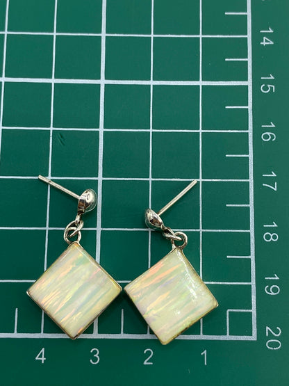 Par de aretes en estuche azul sobre balanza de precisión