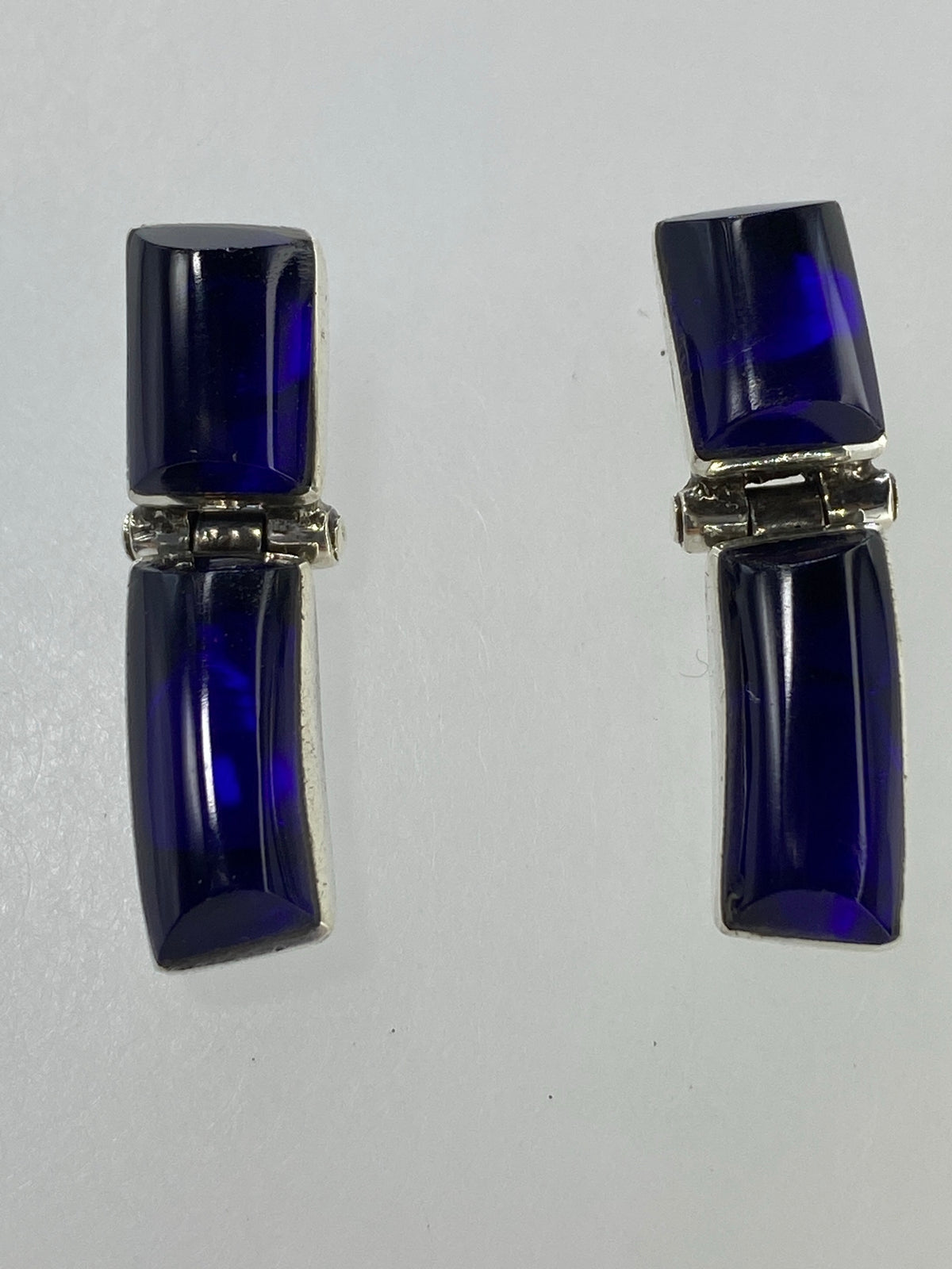 Par de aretes de plata con piedra azul engastada, vista frontal simétrica