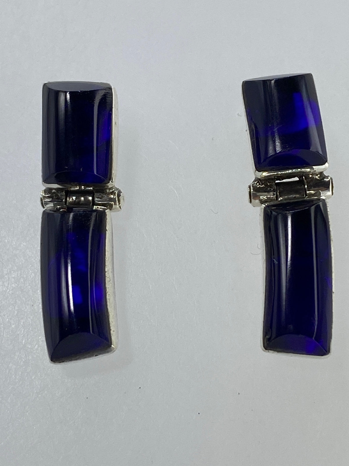 Aretes de plata sobre fondo verde de medición, mostrando tamaño real