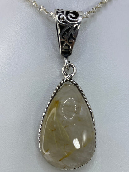 Dije de plata con cuarzo cristalino rutilado, colgando de cadena plateada