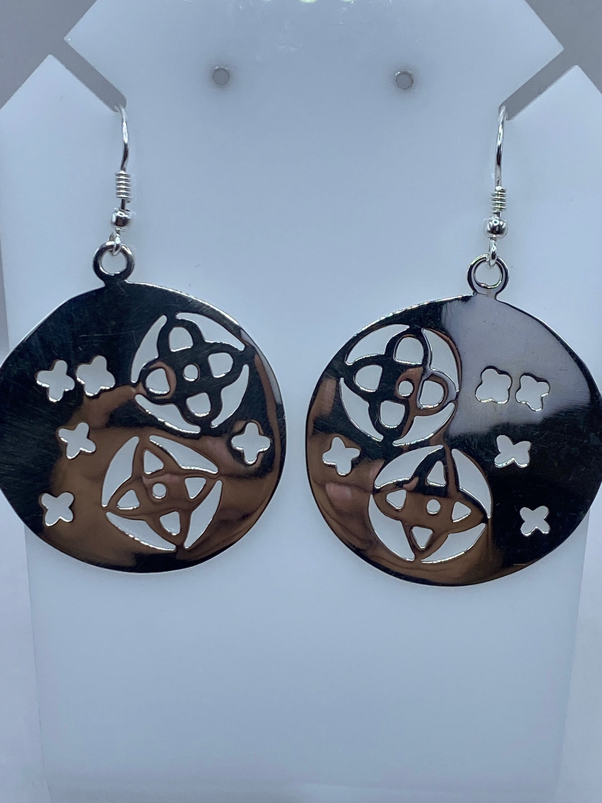 Detalle frontal de los aretes mostrando el corte preciso de calado y la luz atravesando los vacíos