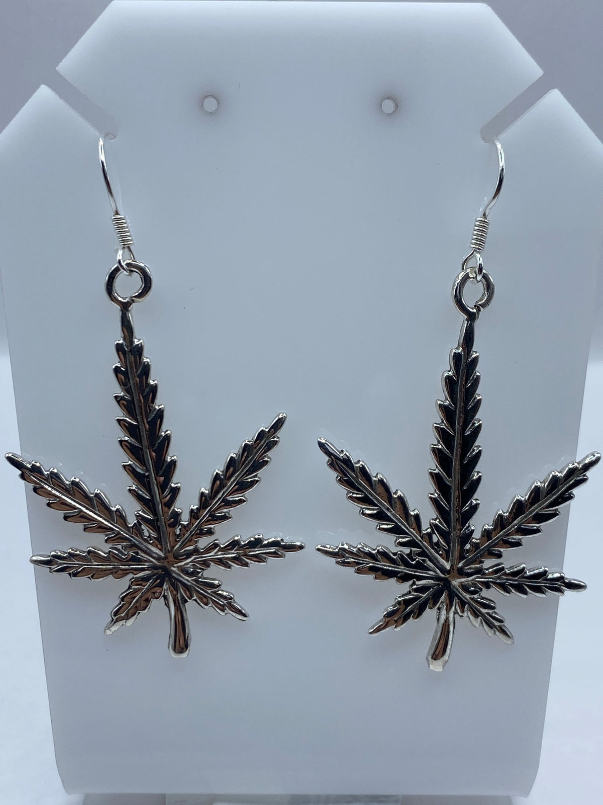 Par de aretes de plata repujada con motivo cannabis estilizado en diseño prehispánico