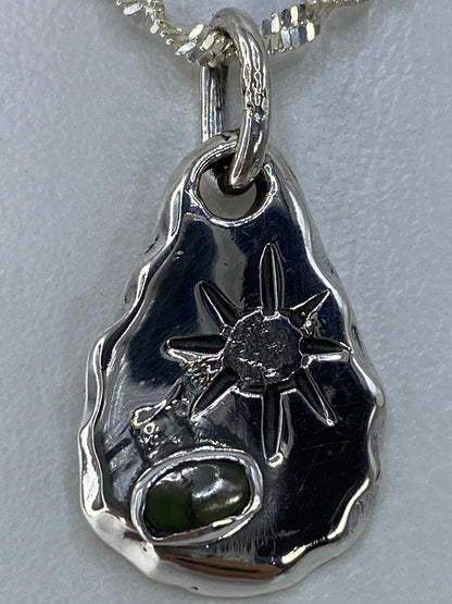 Dije de gota con piedra verde sobre regla de cm mostrando tamaño de 2.9 cm