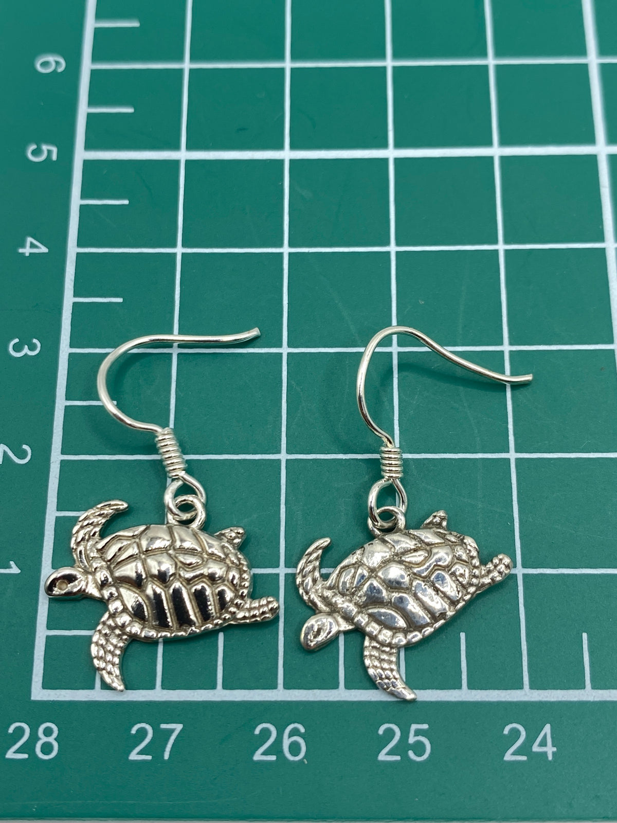 Aretes de tortuga marina en plata pura sobre fondo blanco, listos para usar