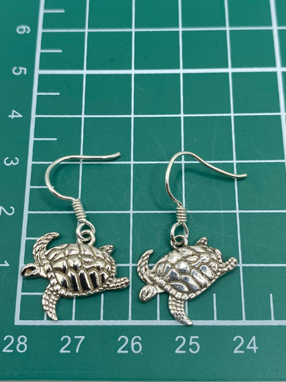 Aretes de tortuga marina en plata pura sobre fondo blanco, listos para usar