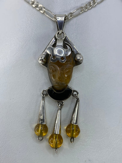 Detalle frontal de la máscara tallada en ámbar con ojos de plata y engaste manual