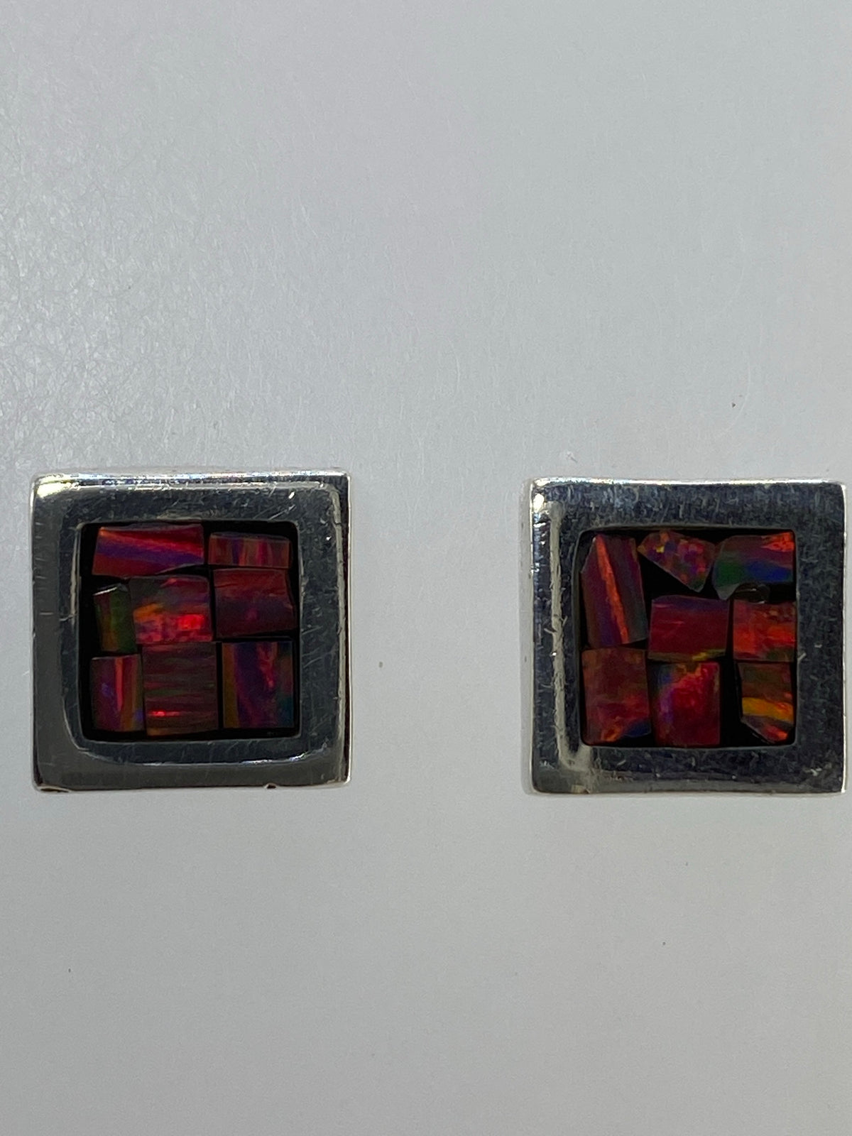 Aretes puestos, luciendo el juego de colores del ópalo bajo la luz natural