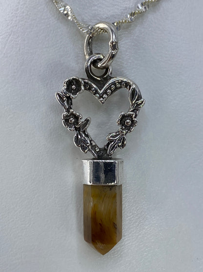 Dije de plata con cuarzo café de 4.5 cm colgando de una cadena plateada