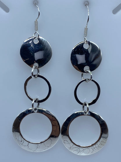 Vista frontal de los aretes eslabonados en plata con textura punteada en los anillos grandes
