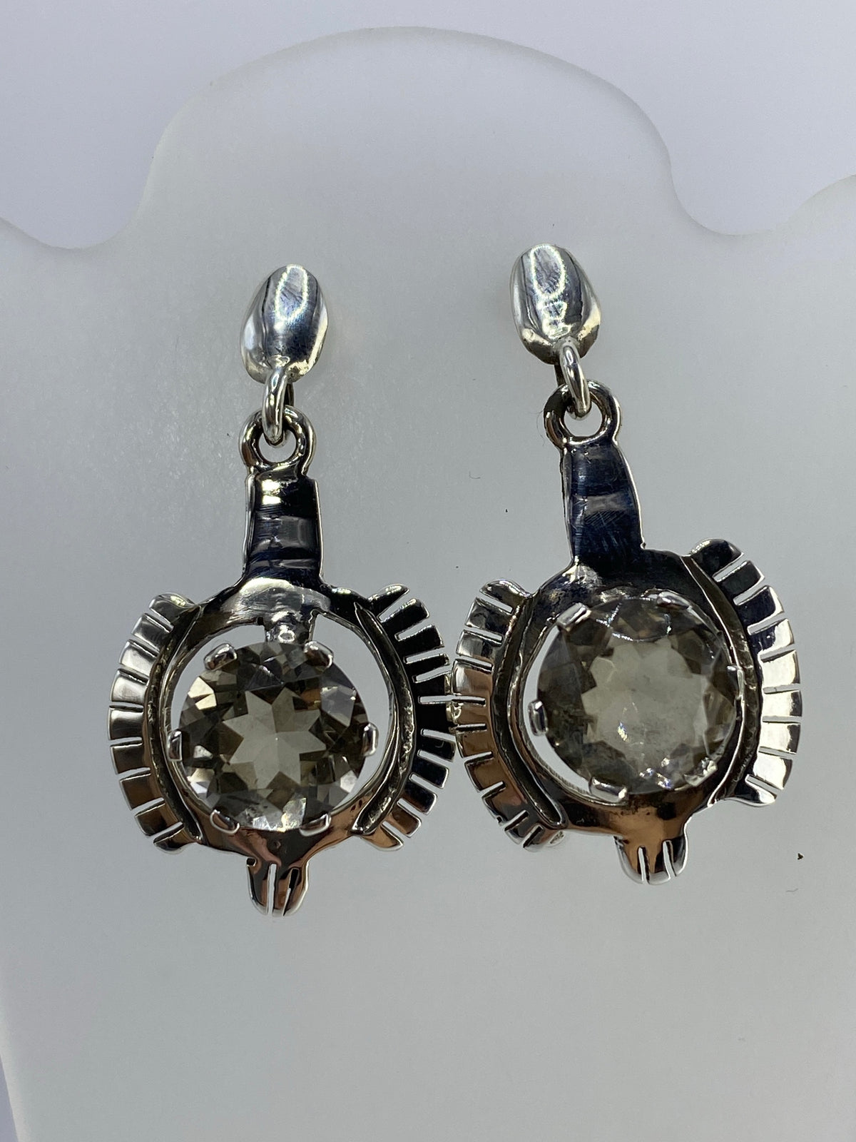 Detalle frontal de los aretes mostrando el engaste radial y la piedra cristalina